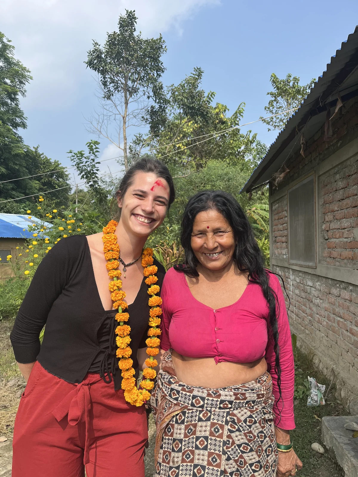 Traveler with traditional marigold garland and local Nepali host