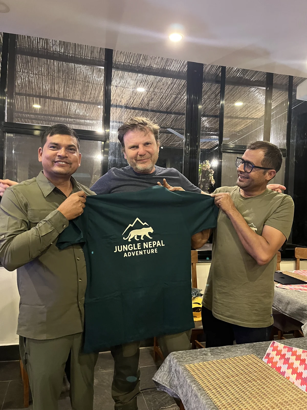 Travelers and guides holding the Jungle Nepal Adventure shirt